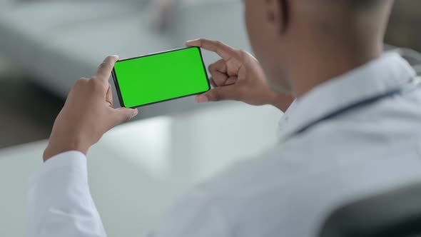 Rear View of African Doctor Looking at Smartphone with Chroma Screen