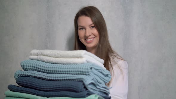 A Young Housewife Woman Holds a Stack of Fresh Washed Clean Linen in Her Hands