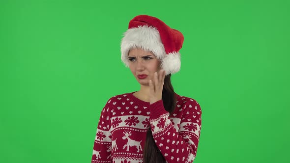 Portrait of Sweety Girl in Santa Claus Hat Is Showing Disgust for Bad Smell or Taste. Green Screen