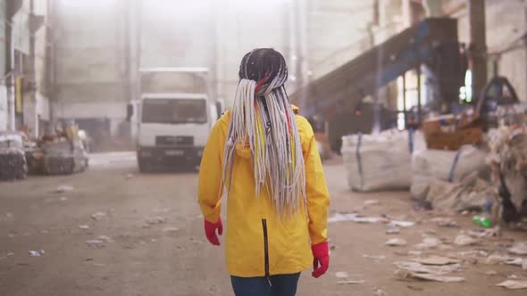 Tracking Rare View Footage of a Girl in Protective Working Clothes Walking By Waste Recycling