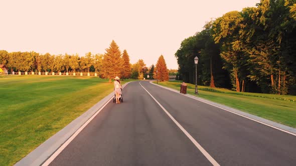 Back View of Girl with Stroller on the Road