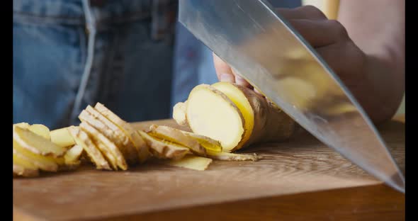 Female Hands Slicing Fresh Ginger for Healing Tea at Home