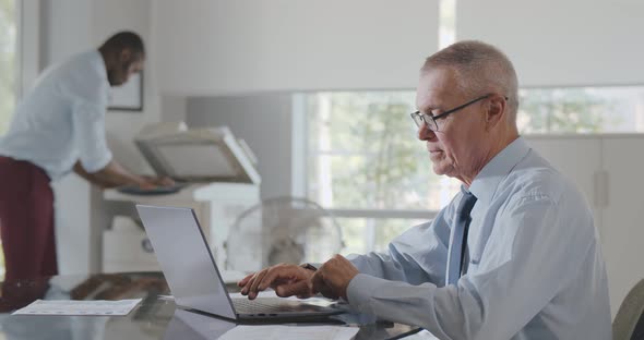Mature Man Suffers From Heat While Working in Office on Laptop