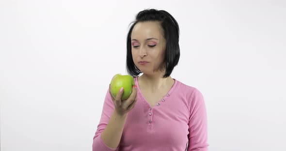 Young Beautiful Woman Eating Big, and Juicy Green Apple on White Background