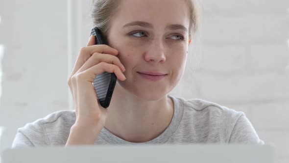 Young Woman Talking on Phone While Working On Laptop