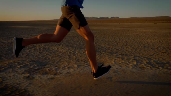 Athletic man working out with battle ropes on a dry lake at sunset