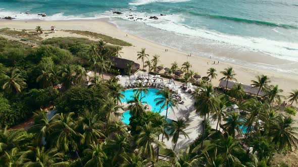 Beautiful beach club surrounded by palm trees overlooking a white sand beach in Oaxaca Mexico