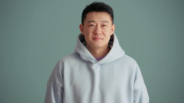 Handsome Asian man wearing hoodie looking at the camera