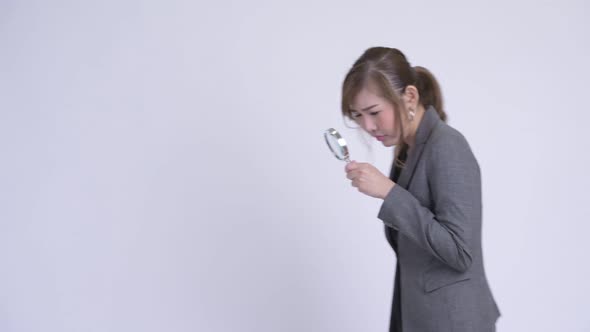 Young Asian Businesswoman Using Magnifying Glass and Looking Shocked