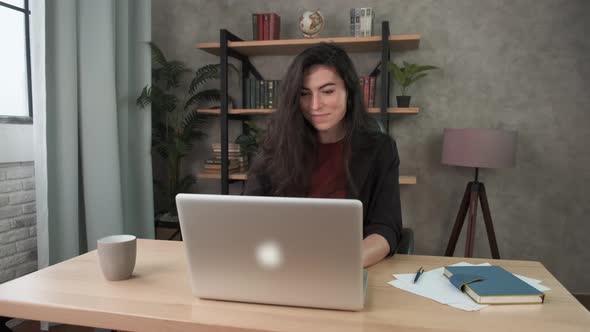 Young Smiling Woman Employee Works in the Office at the Computer. Brunette Girl Looking at Laptop