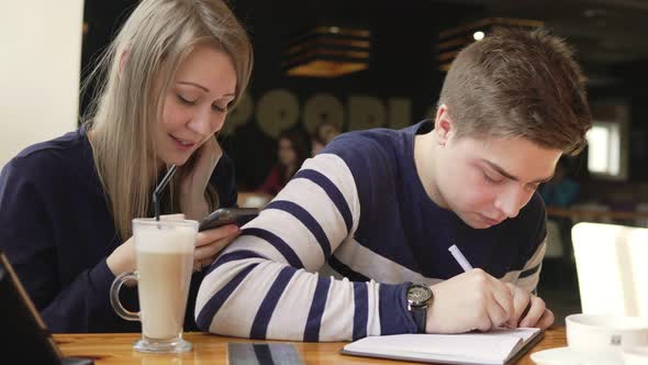 Young Man Writing a Letter or Doing His Homework in a Cafe