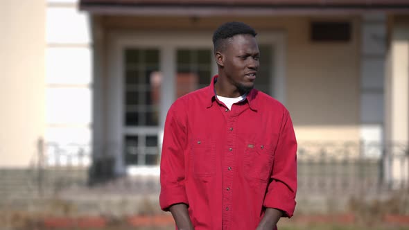 Portrait of Young Man Standing on Sunny Front Yard Looking at Camera with Confident Facial