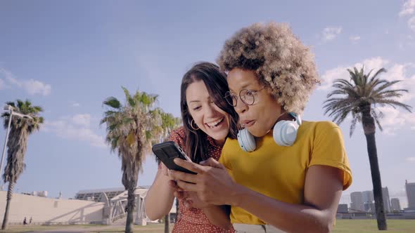 Two Young Women are Watching Something Interesting on the Cell Phone