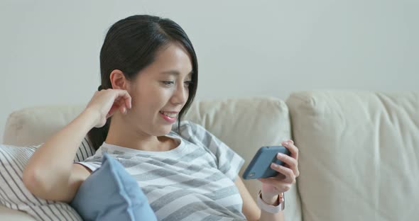 Woman look at mobile phone and sit on sofa