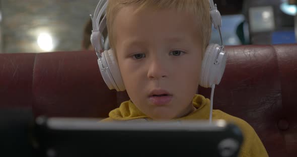 Kid in Headphones Watching Cartoon on Smart Phone