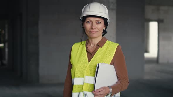 Portrait of female caucasian engineer holding document while standing on construction site.