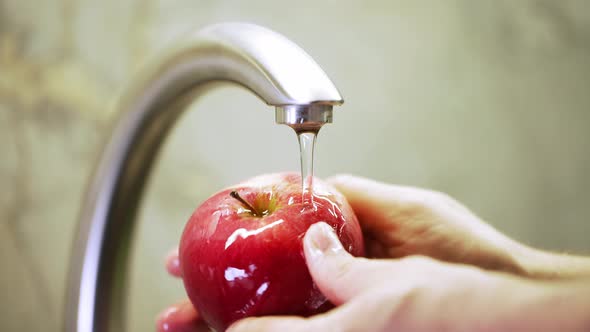 a man washes a red apple. man's hands. water droplets on a flawless clean fruit. freshness diet