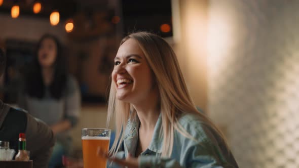 Closeup of a Group of Male and Female Friends Sitting Together in a Bar and Watching a Broadcast on