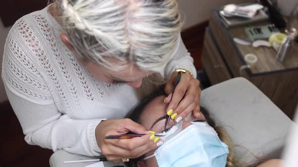 Beautician applying eyelashes on face of woman