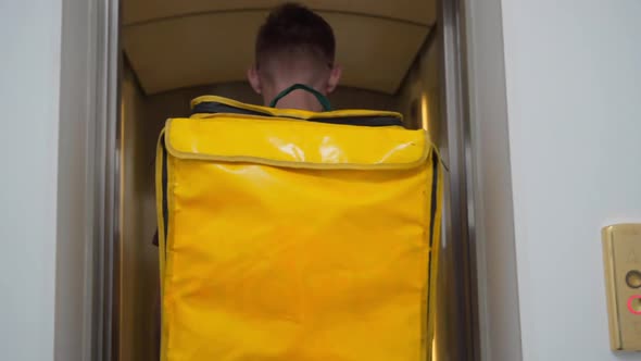 Tracking Shot Young Man Entering Lift with Yellow Insulated Bag Turning Pressing Button