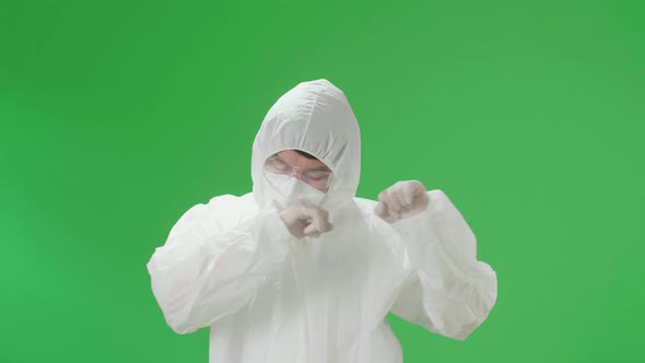 Asian Male Wear Protective Uniform PPE Wearing Medical Face Mask And Dancing In Green Screen Studio