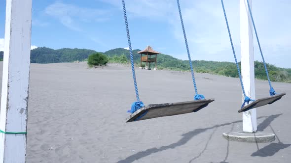 Empty swings swaying in the desert on a hot day