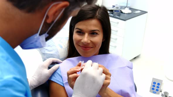 Dentist assisting female patient to wear braces