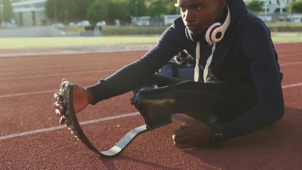 Disabled mixed race man with prosthetic legs stretching before a race