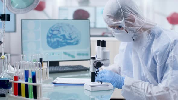 Professional Researcher in Protective Coverall Looking at a Blood Sample alt