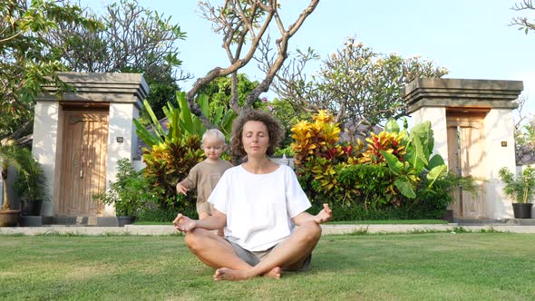 Young Mother Trying to Stay Calm Sitting in Lotus Position While Her Toddler Baby Keep Bothering Her