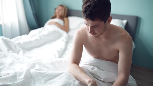 Frustrated Man Sitting on Bed on Different Side of Woman