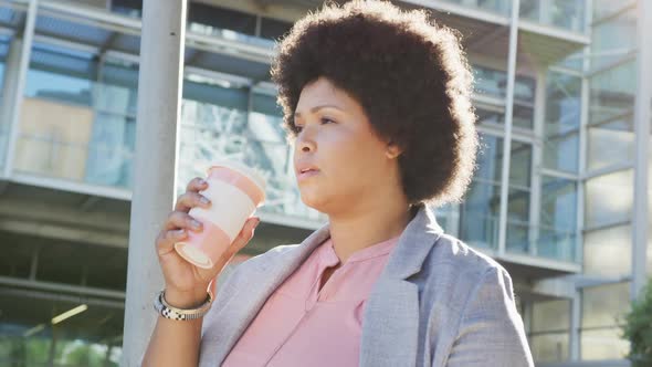 Plus size biracial woman drinking coffee and walking in city