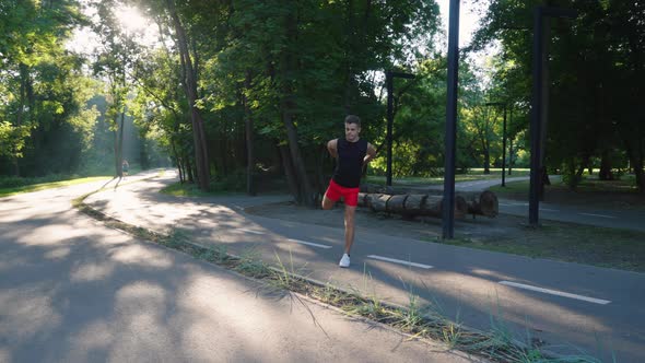 Man Stretching Legs Before Jogging in Park