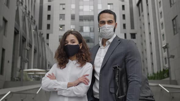 Young Man And Woman In Medical Masks On The Background Of The Office Building