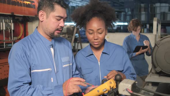 Two professional engineers inspect machines' electric systems at the factory.