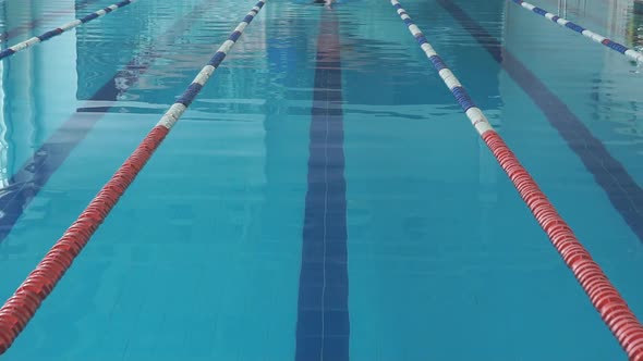 Young Girl in Goggles and Cap Swimming Crawl Stroke Style in the Blue Water Pool