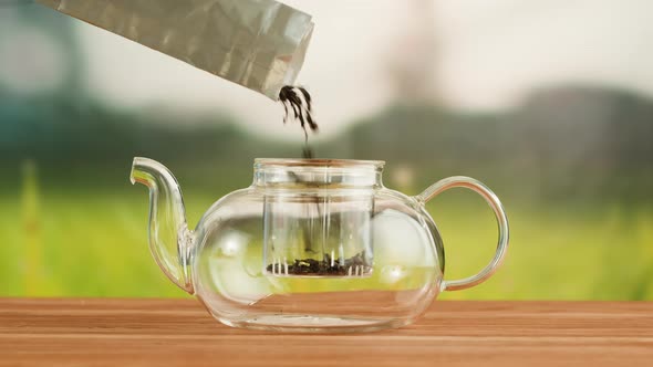Putting Dry Tea Leaves Into Teapot on a Wooden Table