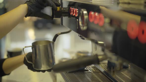 Side View of Unrecognizable Caucasian Barista Beating Milk Using Professional Coffee Machine. Female