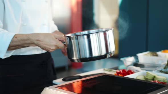 Close-up: The chef adds ingredients to the pot. The process of preparing food in a restaurant.