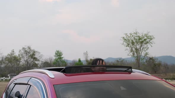 Mother and child enjoying nature along the way in the car on sunroof.