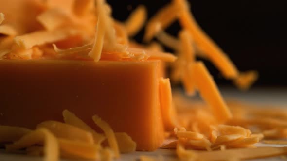 Camera follows grating cheddar cheese. Slow Motion.