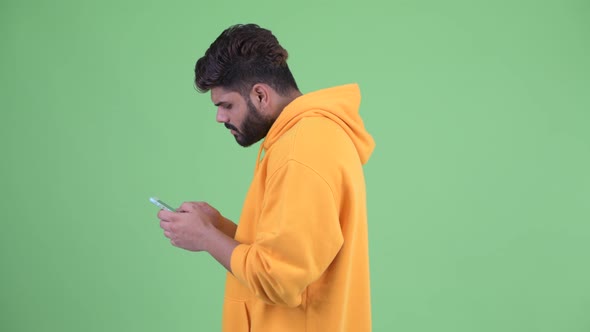 Profile View of Young Overweight Bearded Indian Man with Phone Being Taken Away