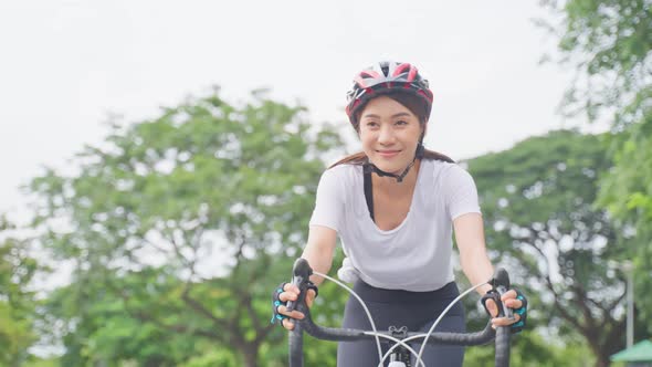 Asian young sport woman riding bicycle in the evening in public park.