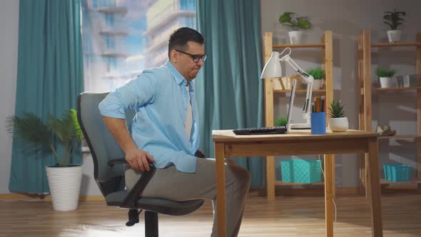 a Man an Office Worker or Freelancer Sitting on an Uncomfortable Office Chair Feels Uncomfortable