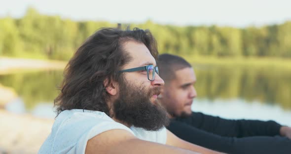 Closeup of the Face of Two Men Sitting By a Lake They are Listening to Music By the Fire a Boy with