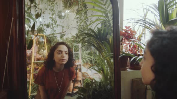 Girl Looking in Mirror in Plant Filled Room