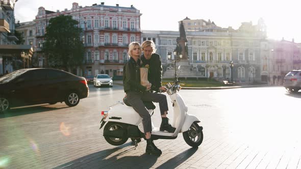 Hortrait of Happy Young Hipster Couple Sitting on a Vintage Scooter in Old City Center with Grocery