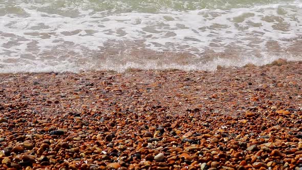 Background shot of waves breaking on the stony shore at Bright in England on a sunny day.