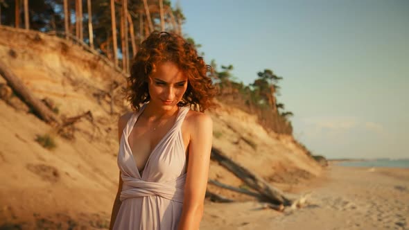 Fit Young Woman is Looking at you and Walking Against Sunset Sea Background