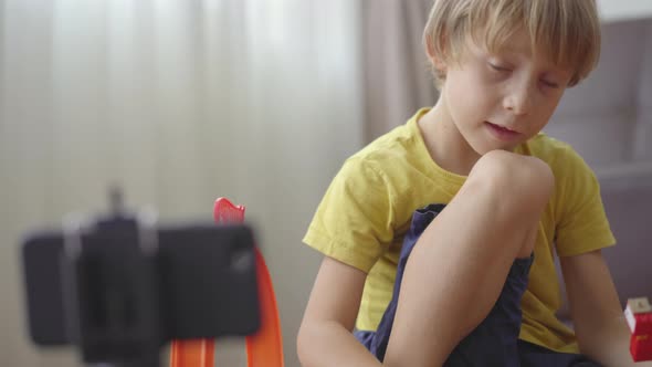 A Little Boy Plays and Talks with His Friends and Relatives Through a Video-call Using a Smartphone